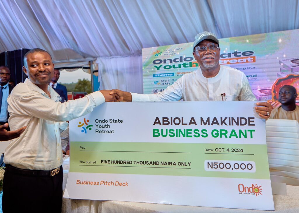 Governor Aiyedatiwa presenting a business grant cheque of 500 thousand Naira to a youth at the Ondo Youth Retreat.